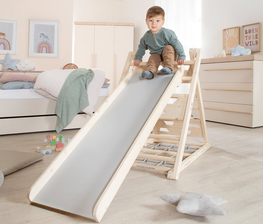 Ein Junge klettert auf ein roba Kletterdreieck mit Rutsche im Kinderzimmer.