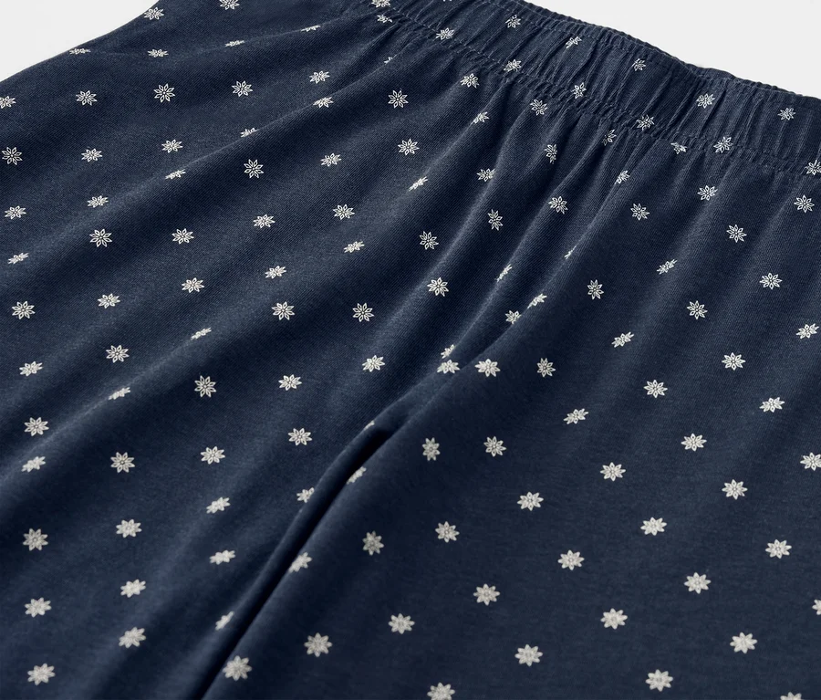Detailaufnahme einer dunkelblauen Hose mit weißen Blumen und elastischem Bund.
