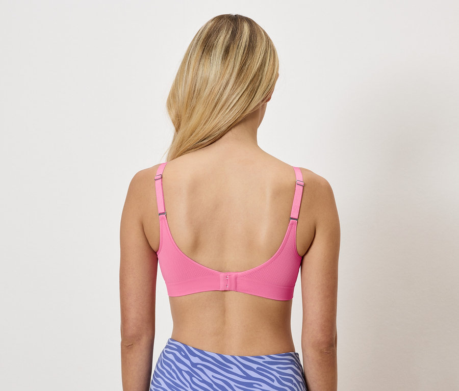 Rückansicht einer Frau mit blonden Haaren, die einen pinkfarbenen BH und blaue Leggings mit Tiermuster trägt.