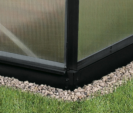 Ecke eines Vitavia Gewächshauses Orion ESG 3,8 m² inkl. Rahmenfundament auf Rasen mit Kiesbett.