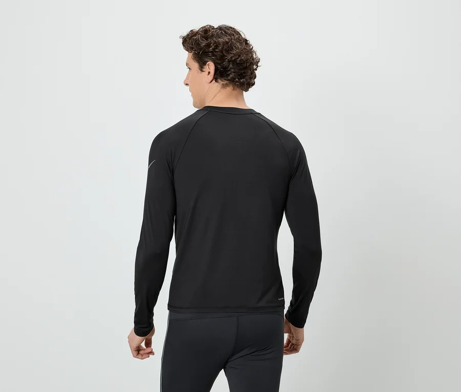 Rückansicht eines Mannes mit lockigem Haar, der ein schwarzes Langarmshirt und eine schwarze Hose vor einem weißen Hintergrund trägt.