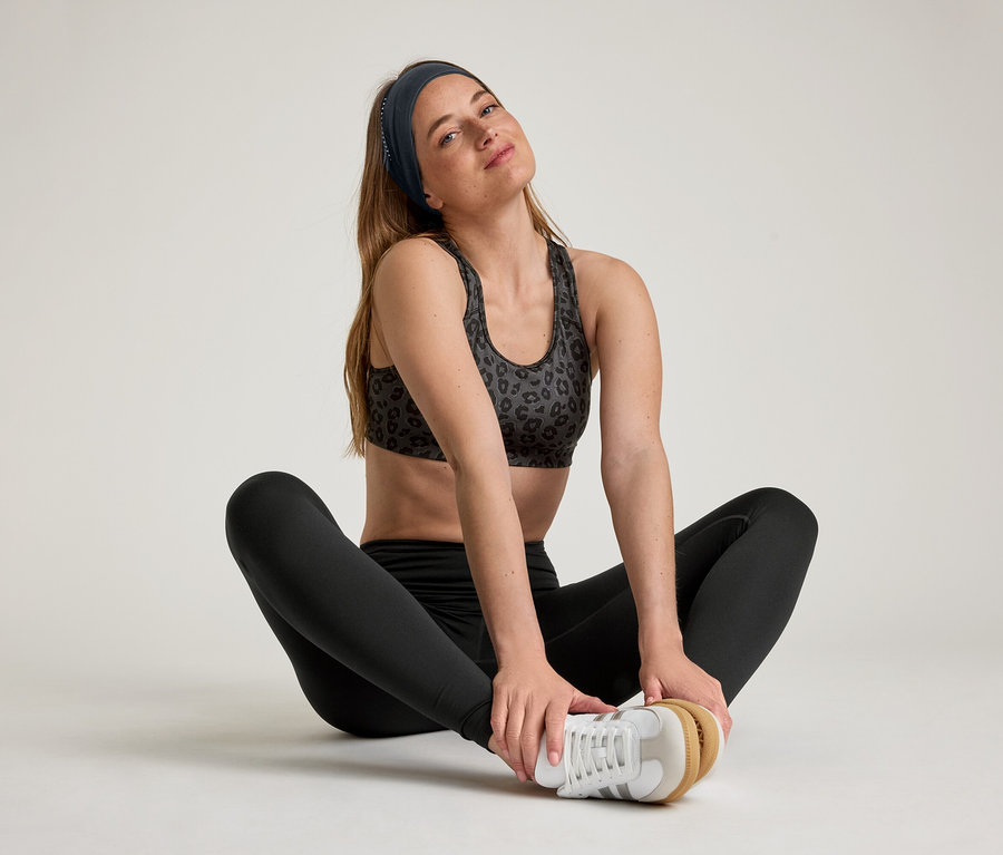 Frau sitzt mit gespreizten Beinen und trägt Sportleggings »ActiveSoft«.