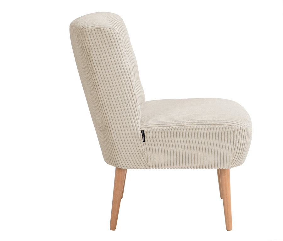 Ein cremefarbener Cord-Sessel steht im Profil.
