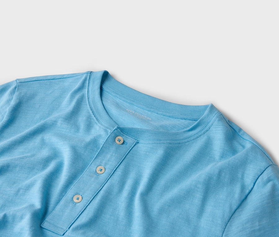 Nahaufnahme eines hellblauen Henley-Shirts mit drei Knöpfen.