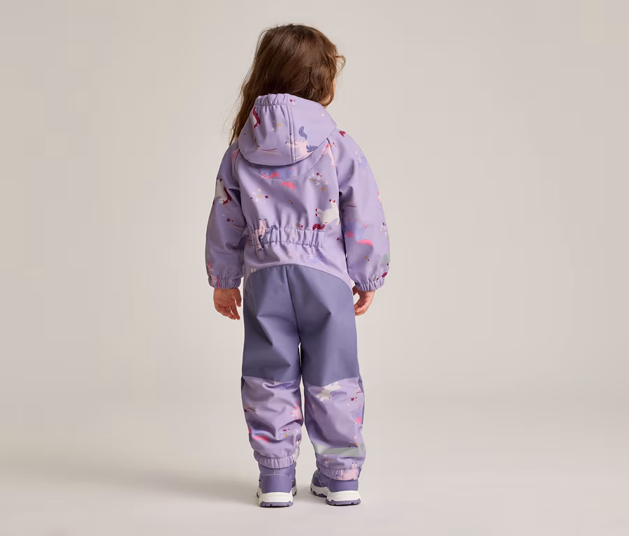 Rückansicht eines Kindes mit langen braunen Haaren, das eine lila Regenjacke mit Kapuze und passender Regenhose mit Einhornmuster trägt.