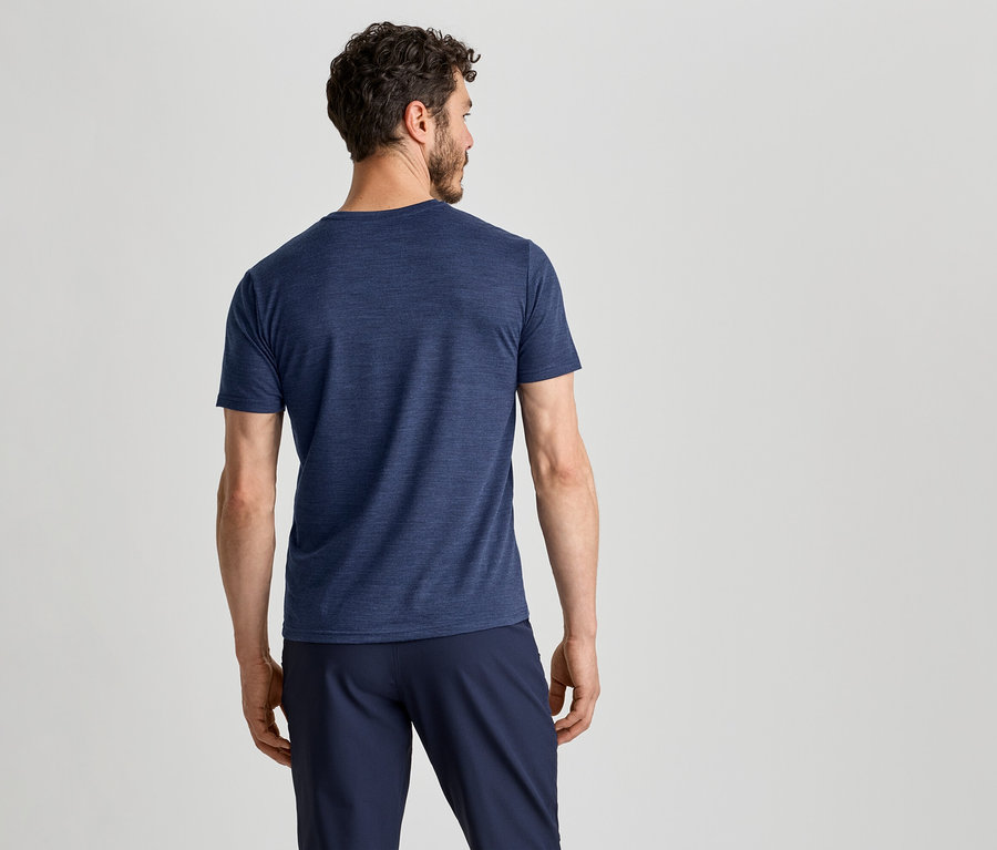 Ein Mann von hinten, der ein dunkelblaues T-Shirt und eine dunkelblaue Hose trägt und nach rechts blickt.