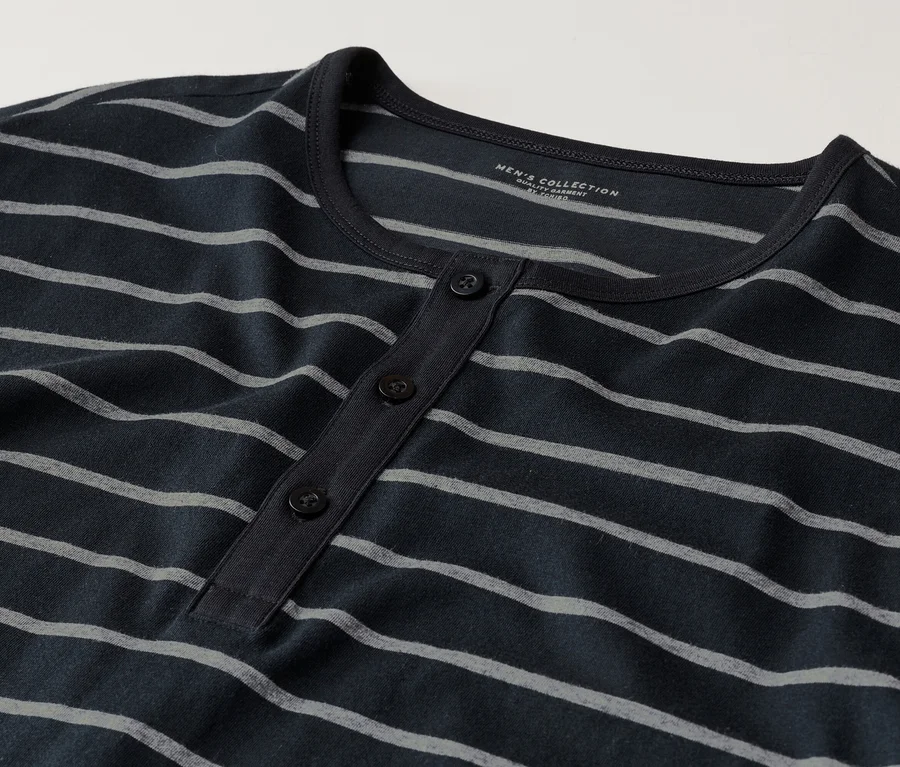 Nahaufnahme eines dunkelblauen, langärmeligen Henley-Shirts mit grauen Streifen und drei Knöpfen.