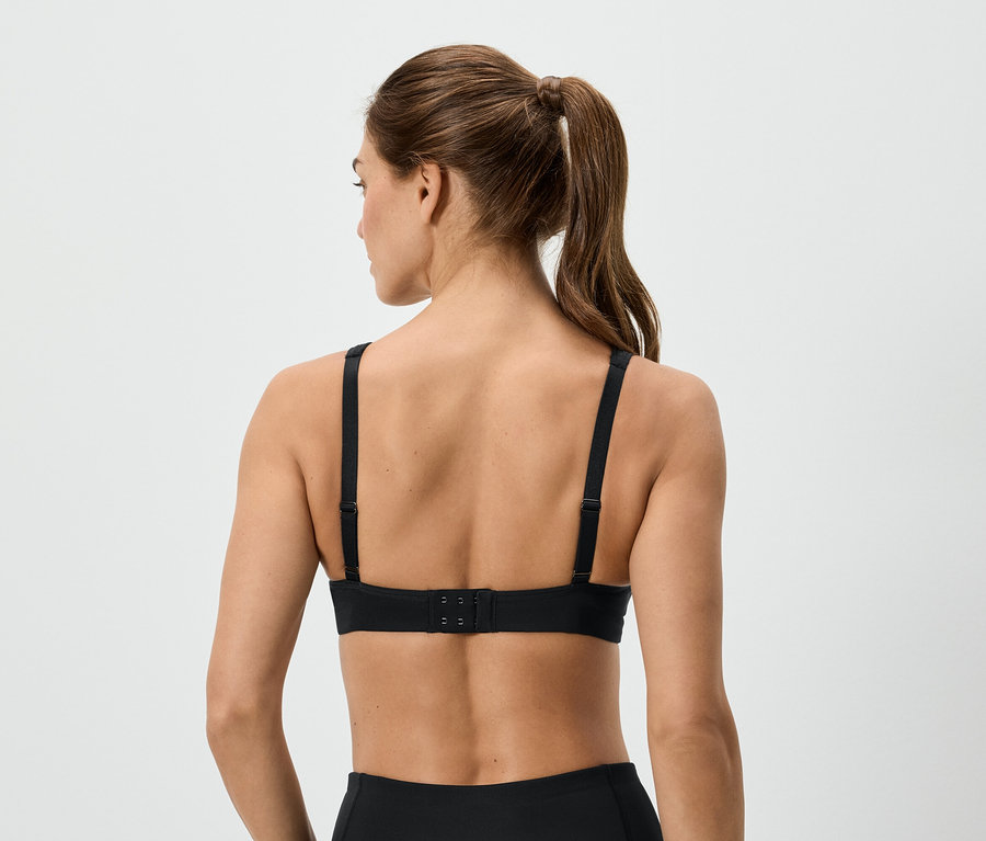 Rückansicht einer Frau mit Pferdeschwanz, die einen schwarzen Sport-BH trägt.