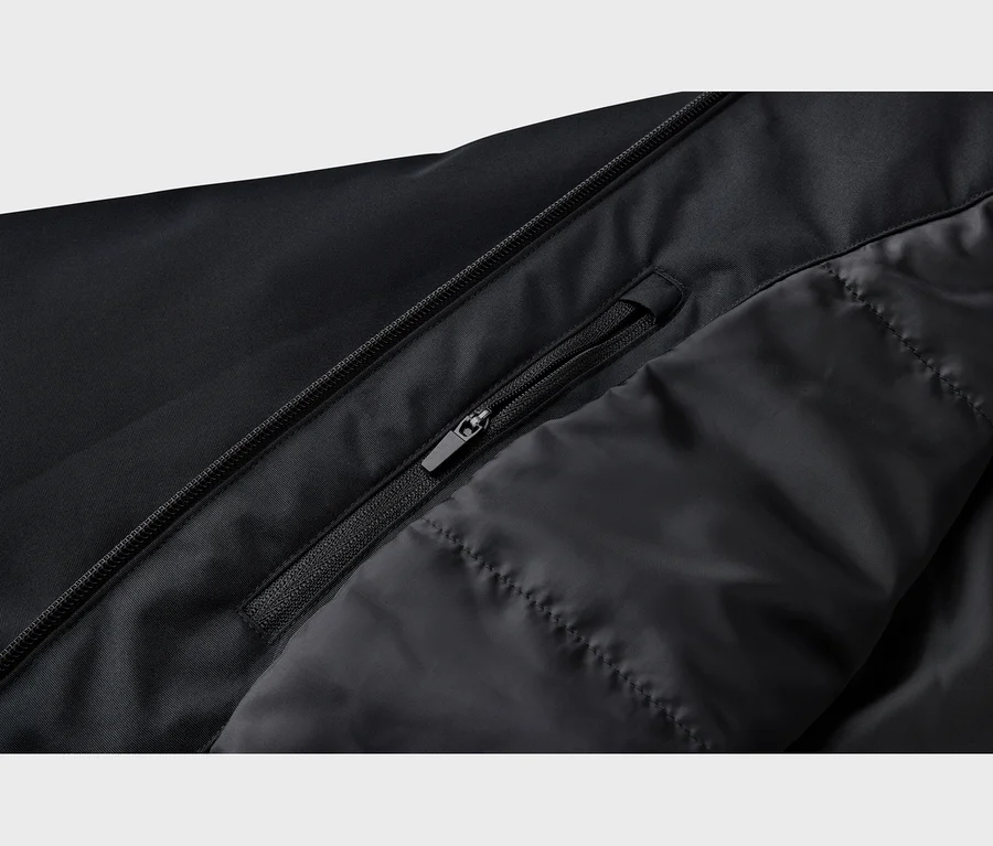 Nahaufnahme einer schwarzen Jacke mit einem Hauptreißverschluss, einer teilweise geöffneten Reißverschlusstasche und gestepptem Innenfutter.
