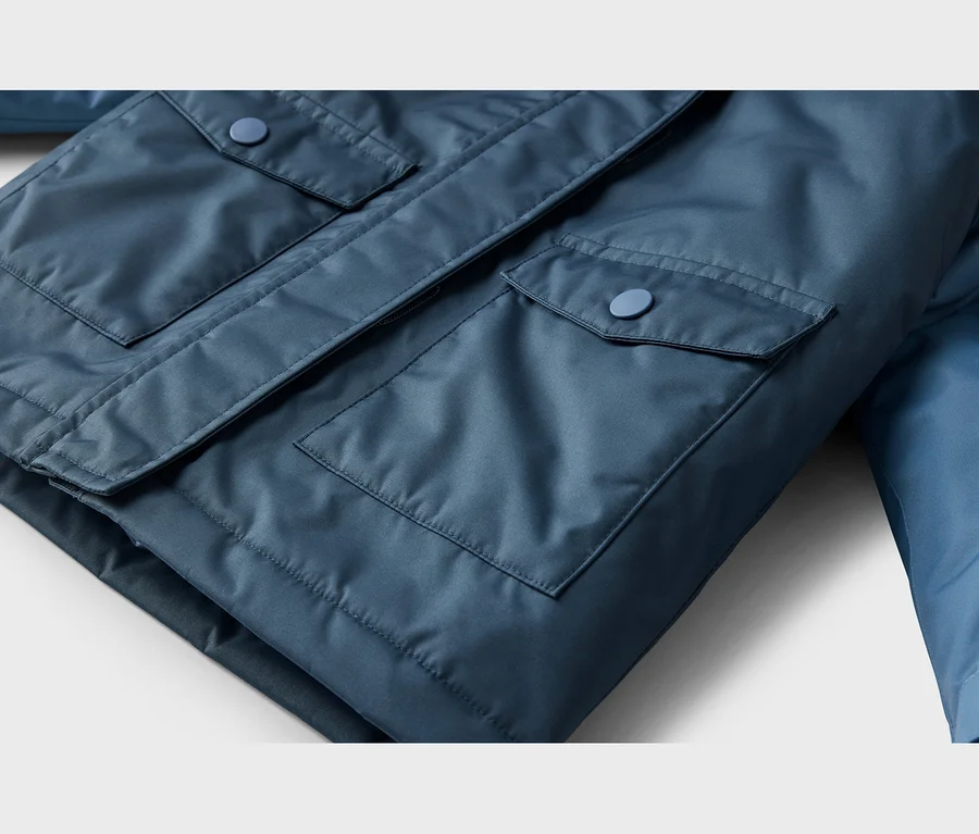 Nahaufnahme einer blauen Jacke, die zwei Pattentaschen mit passenden blauen Knöpfen zeigt.
