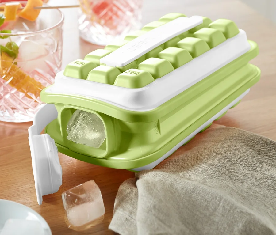 Grüner Eiswürfelbereiter »ICEBREAKER® POP« auf einem Tisch neben Getränken.