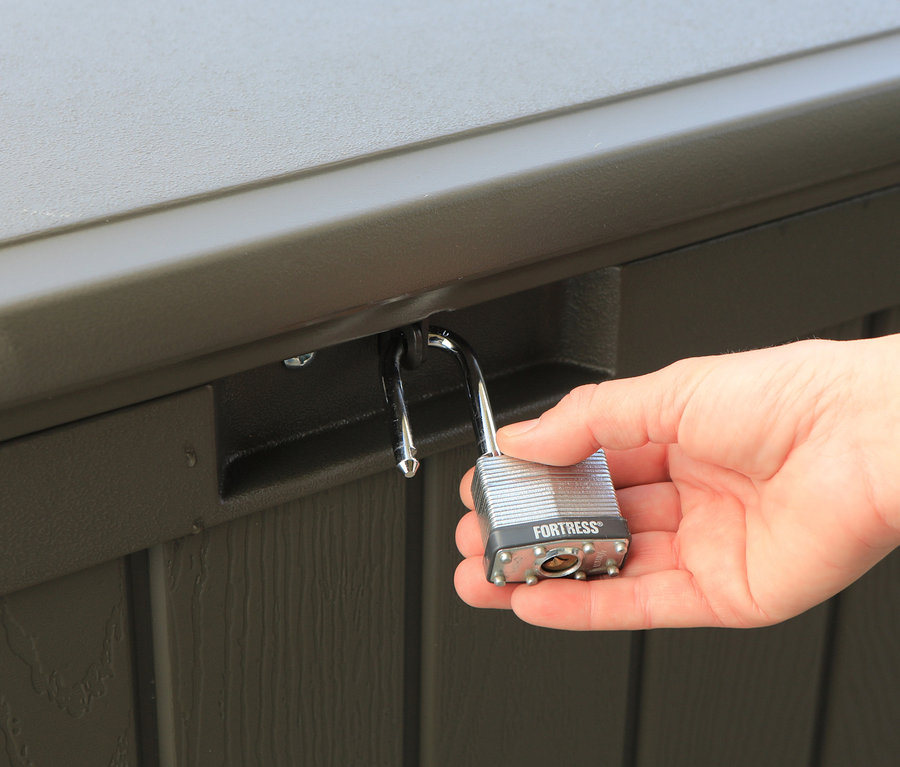 Eine Hand hält ein Vorhängeschloss an einer braunen Kissenbox (ca. 440 l).