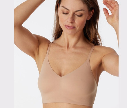 Frau berührt ihre Haare und trägt ein SCHIESSER Invisible Bustier mit Pads, maple.