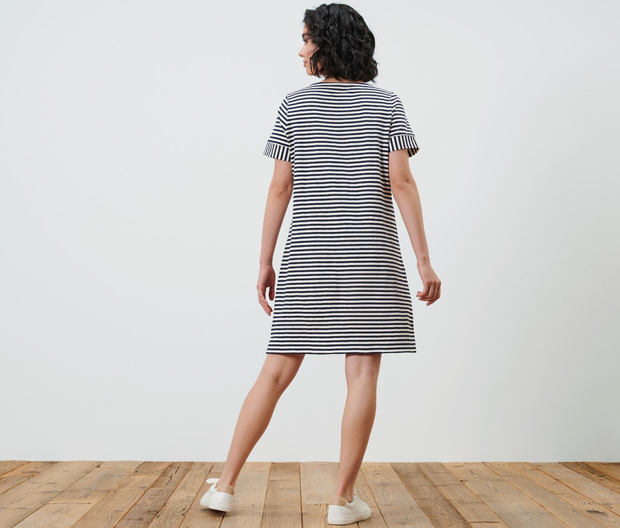 Frau steht mit dem Rücken zur Kamera und trägt ein gestreiftes Jerseykleid.