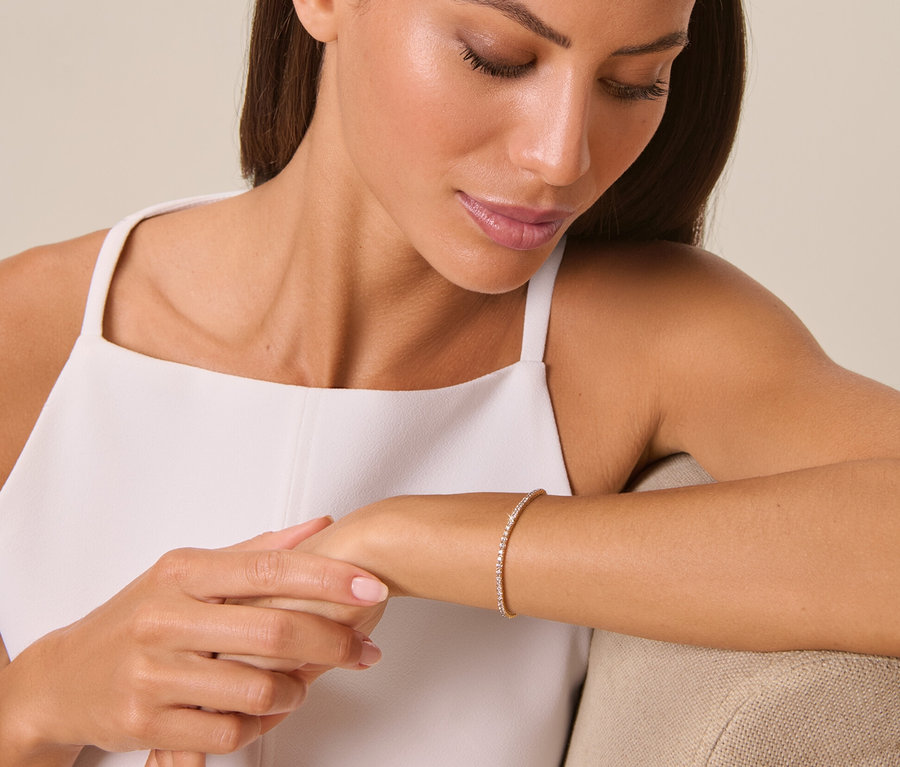 Frau betrachtet 585 Gold-Armband mit 81 Brillanten am Handgelenk.