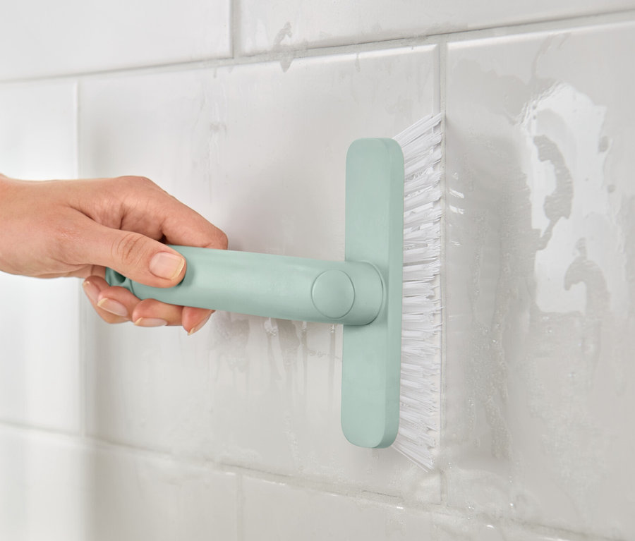 Eine Frau reinigt Fliesenfugen mit dem 4-in-1-Fugenmeister.