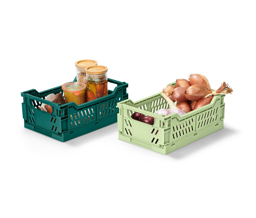 Zwei klappbare Ordnungskisten, eine grüne mit Konserven, eine hellgrüne mit Zwiebeln und Knoblauch.
