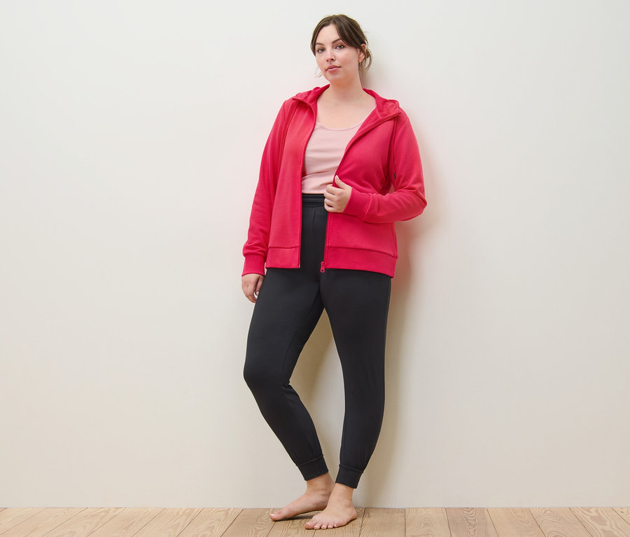 Frau posiert in pinker Sweatjacke, Yogahose und 2 Tops, rosé/pink.