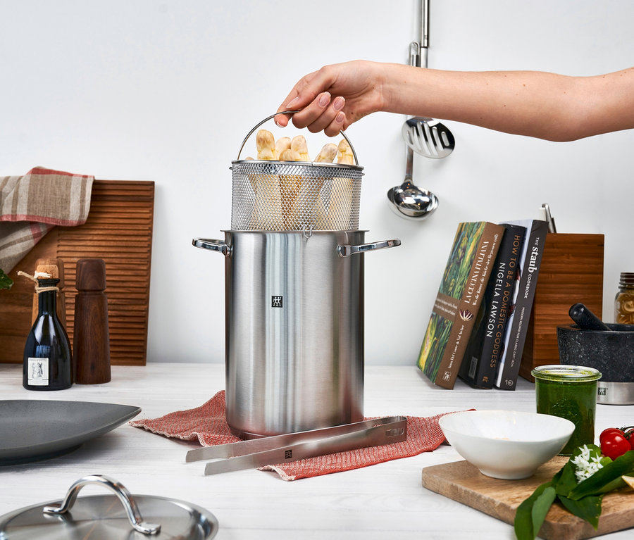 Eine Hand hält einen Edelstahldrahtkorb mit gekochtem Gemüse über einem 16 cm ZWILLING Spargel-/ Nudeltopf »Twin Specials«.