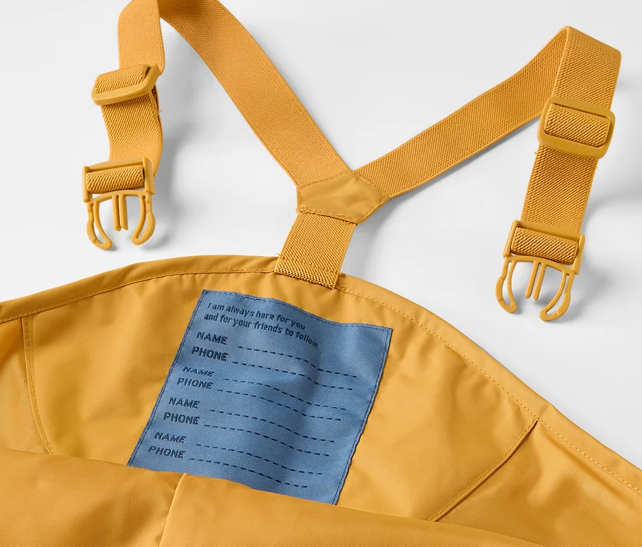 Detailaufnahme einer Kinder-Regenhose mit Latz und gelben Trägern.