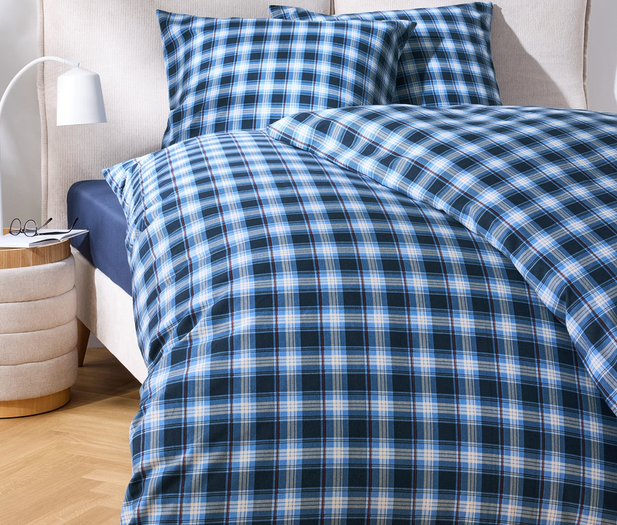 Bettwäsche mit blauem Karomuster auf einem Bett.