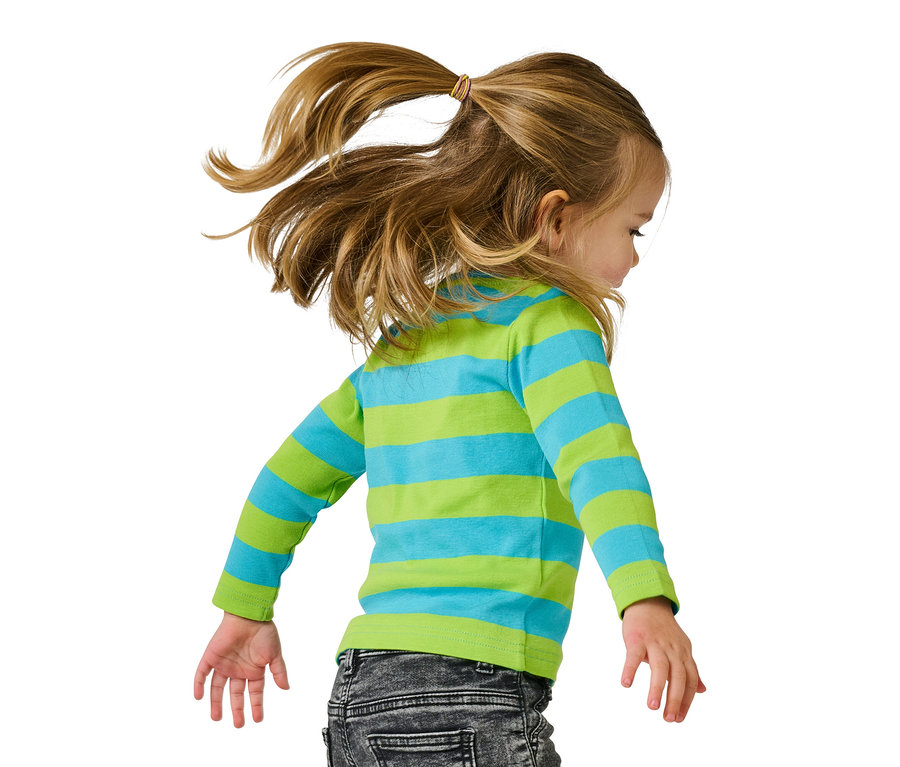 Mädchen mit blonden Haaren im Pferdeschwanz, gestreiftem Shirt und Jeans, blickt nach unten.