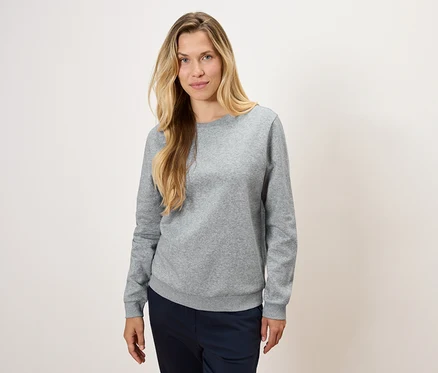 Frau trägt einen grauen Pullover und dunkelblaue Hosen.