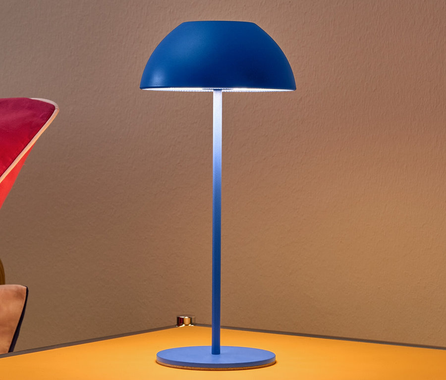 Blaue LED-Akku-Tischleuchte auf gelbem Nachttisch.