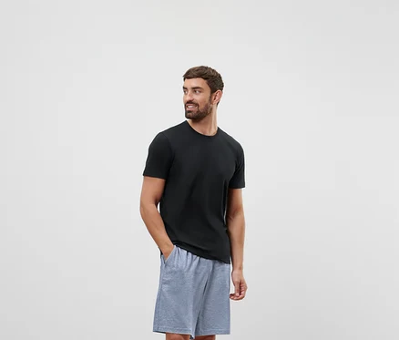 Mann in schwarzem T-Shirt und grauen Shorts blickt nach rechts.