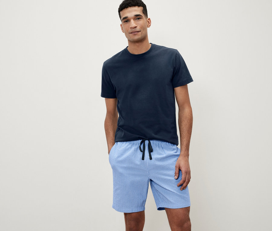 Mann posiert in einem Shorty-Pyjama-Set mit gewebter Hose.