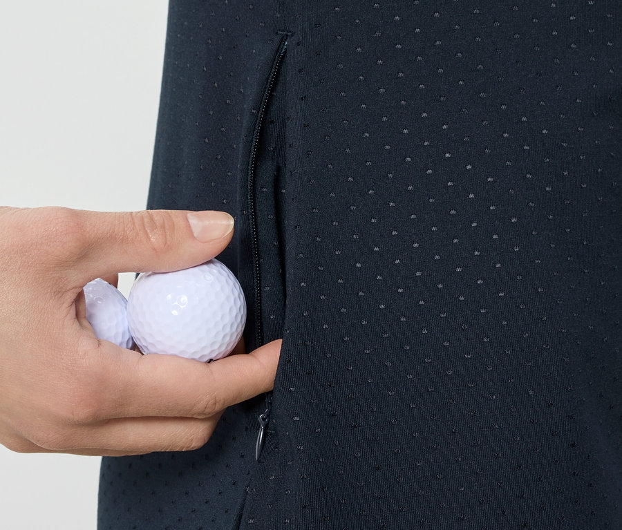 Hand legt Golfbälle in die Tasche eines Sportkleids.