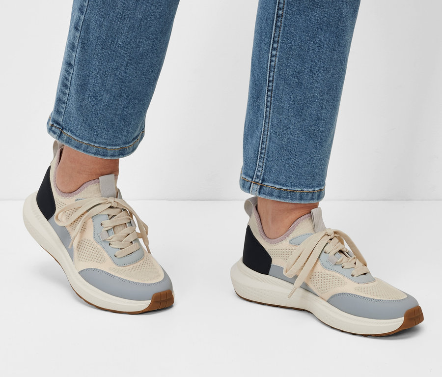 Beine in Jeans und Sneaker auf weißem Hintergrund.