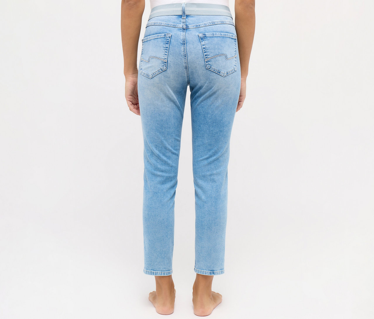 Rückansicht einer barfüßigen Frau, die eine hellblaue Angels Jeans »Ornella Sporty« Slim Fit 7/8 trägt.