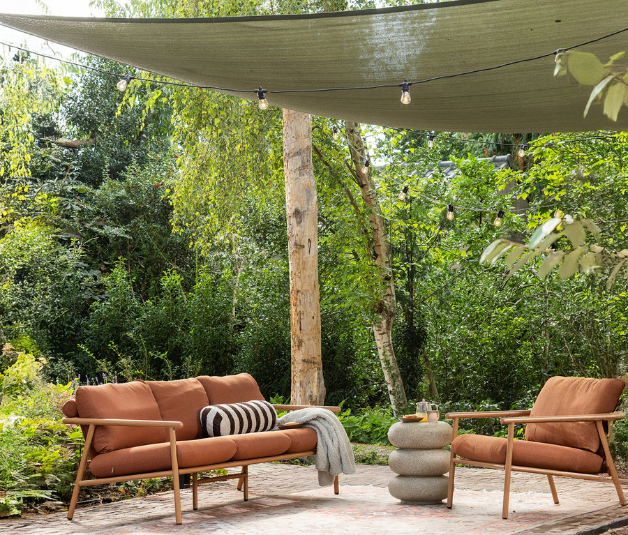 Ein braunes Sofa und ein Sessel stehen auf einer Terrasse, neben einem runden, beigen WOOOD Beistelltisch.