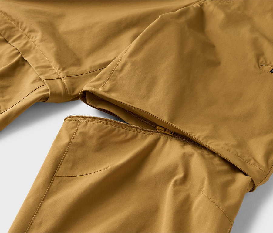 Nahaufnahme einer khakifarbenen Hose mit abzippbarem Bein, das teilweise mit einem Reißverschluss befestigt ist.