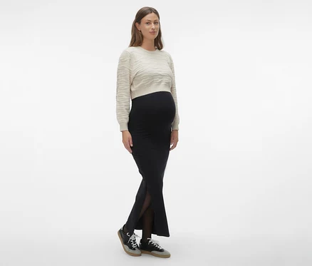 Frau trägt MAMALICIOUS Maxirock »MLEMMA TUBE« in Schwarz, dazu einen hellen Pullover und Turnschuhe.