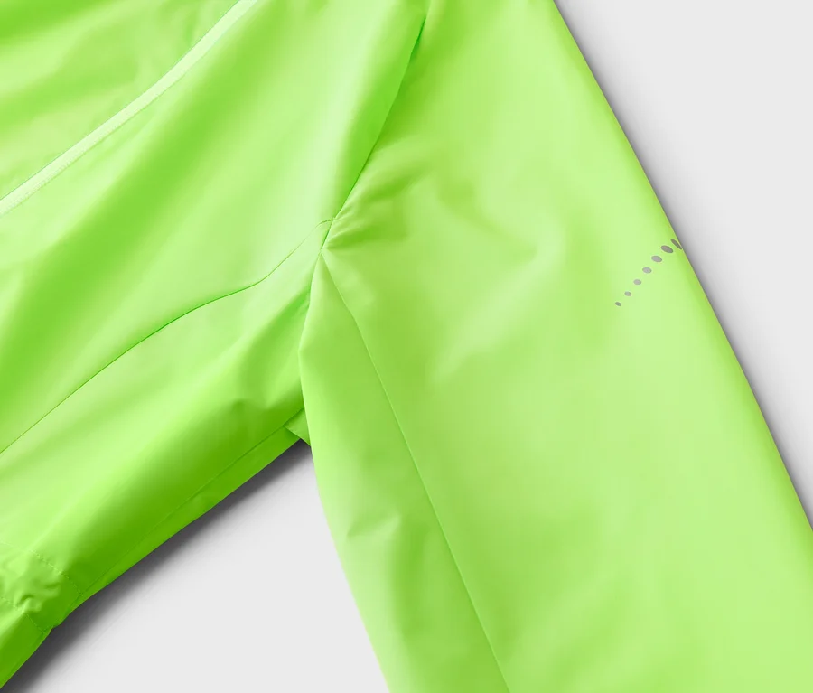 Nahaufnahme einer neongrünen Jacke mit reflektierenden Punkten am Ärmel auf weißem Hintergrund.