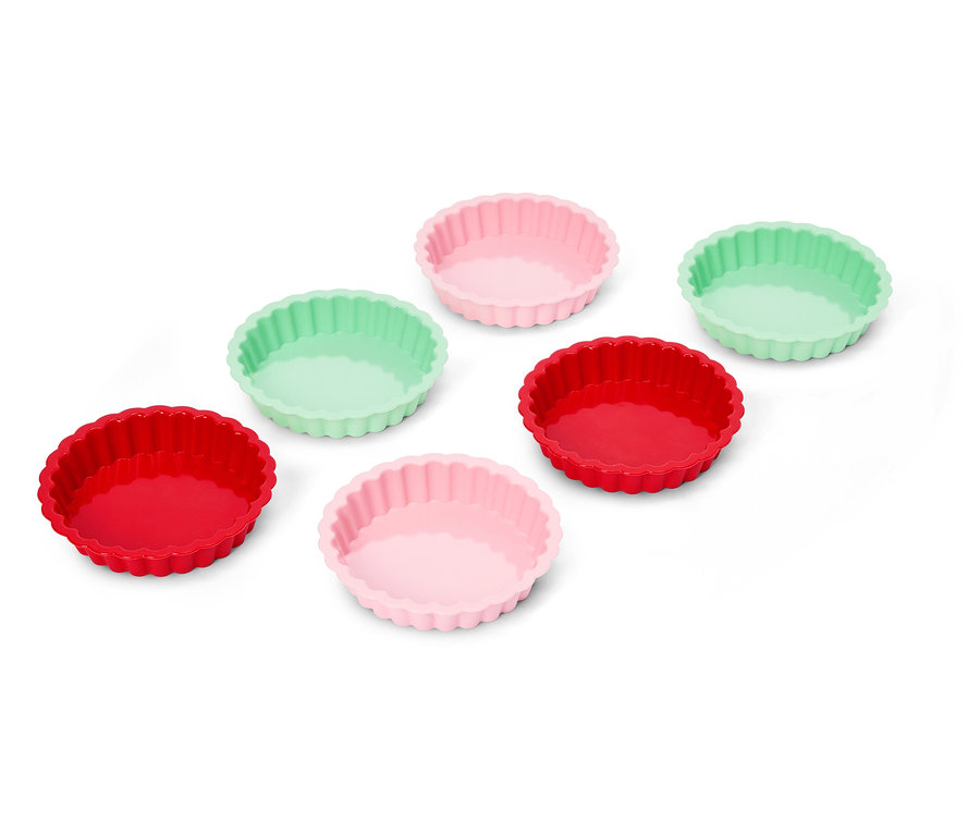 Sechs Silikon-Tarteformen in Rot, Rosa und Mintgrün sind auf einer weißen Oberfläche angeordnet.