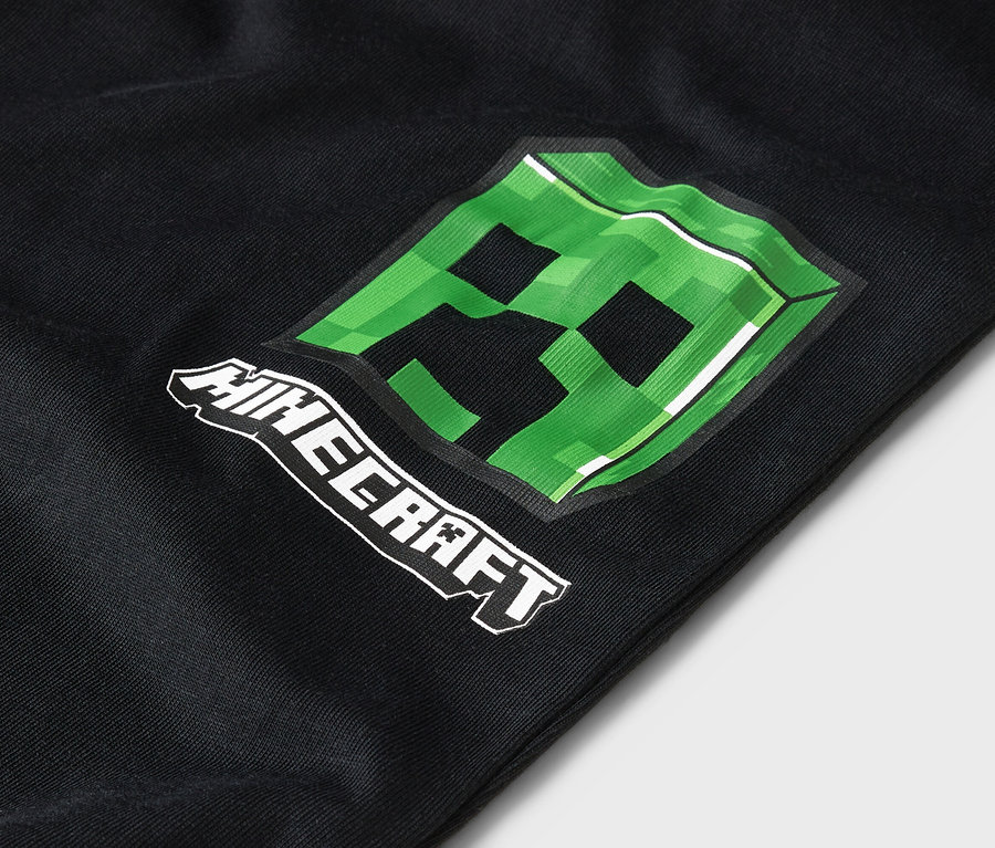 Detailansicht von schwarzer Kleidung mit einem grünen Minecraft-Creeper-Design.