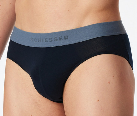 Ein Mann trägt schwarze SCHIESSER Slips mit grauem Bund, auf dem der Markenname steht.