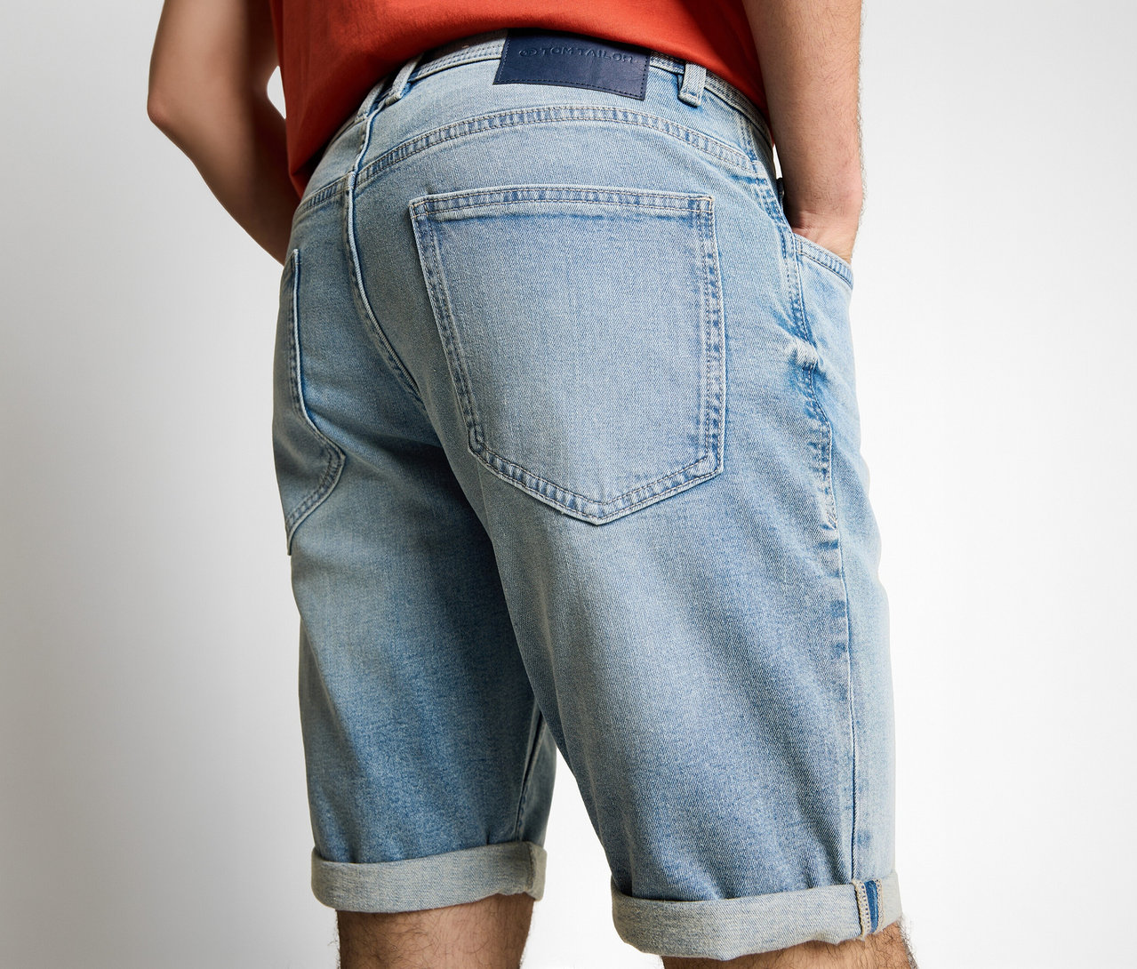 Mann von hinten mit Tom Tailor TTJOSH REGULAR SLIM Jeans Shorts in Light Stone Blue Denim, Hände in den Hosentaschen.