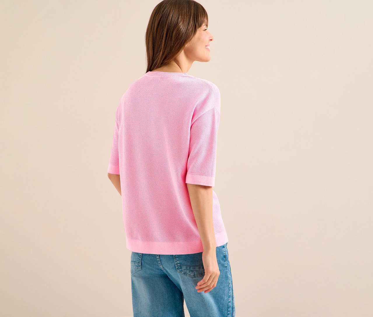 Frau von hinten mit pinkem CECIL Kurzarmpullover und Jeans.