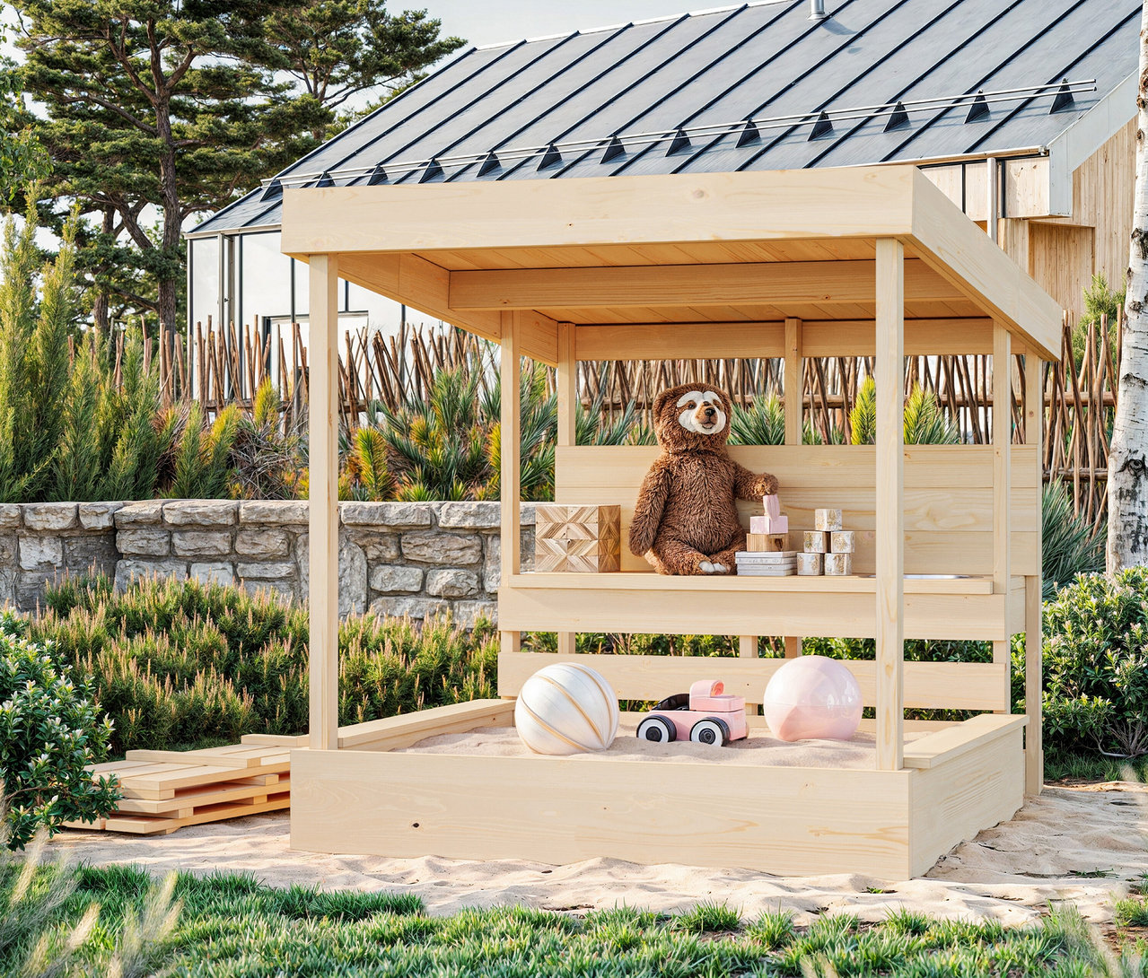 Ein Teddybär sitzt auf einer Bank in einem Sandkasten mit Spielzeug.
