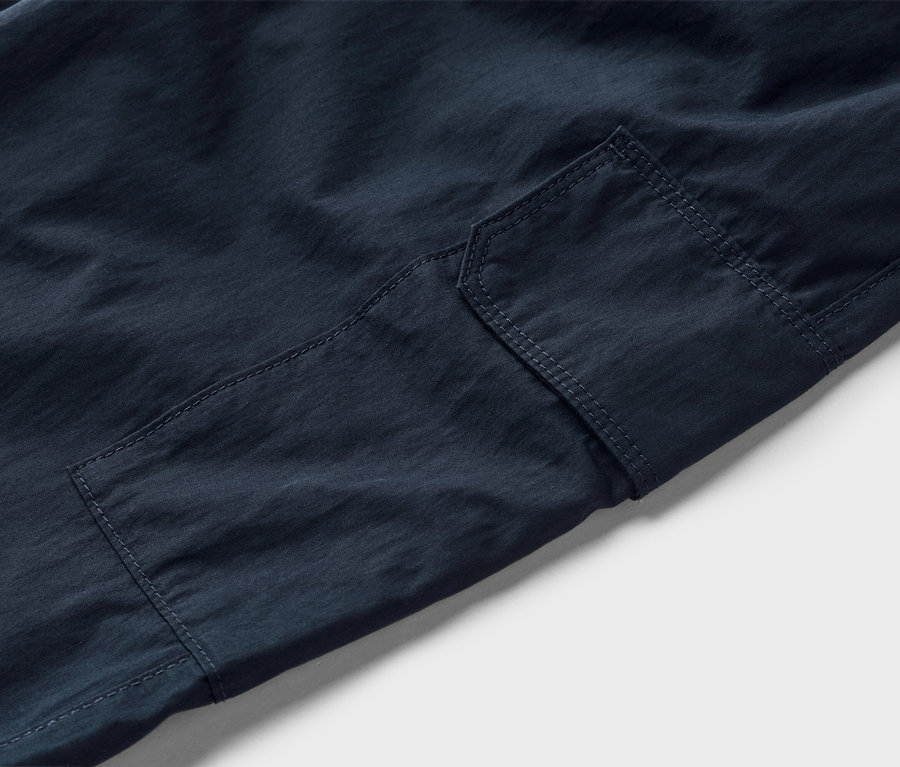 Nahaufnahme einer dunkelblauen Cargohose mit aufgesetzter Tasche.