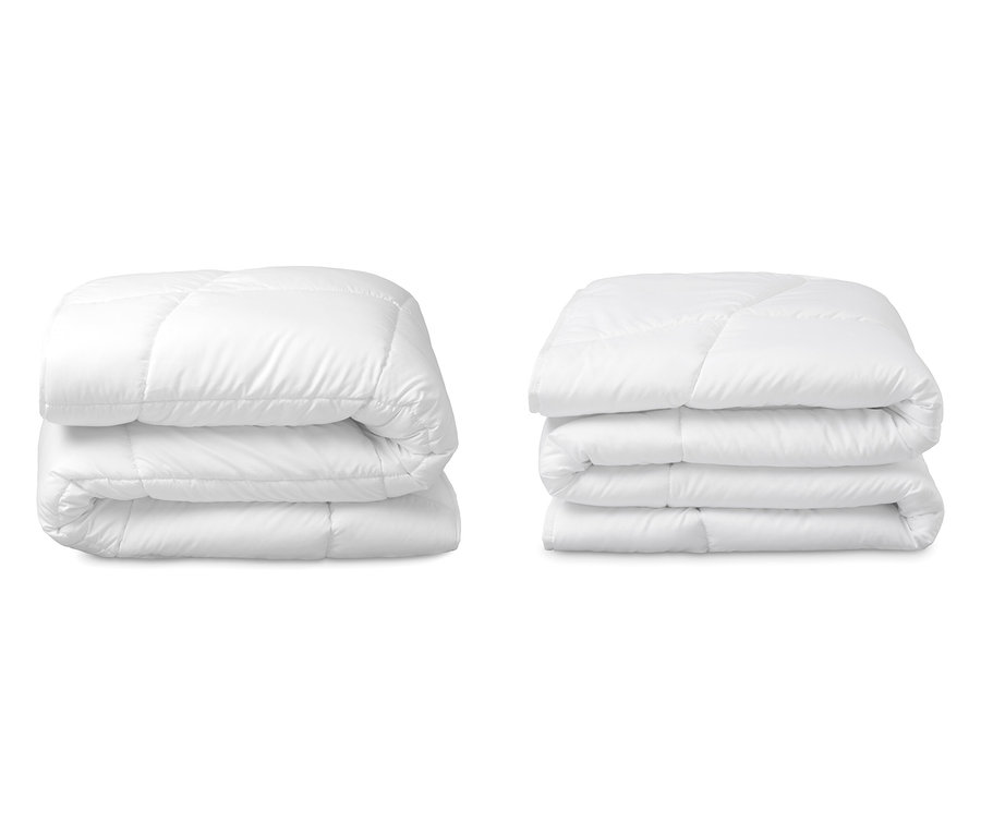 Zwei gestapelte, weiße Home By TEMPUR® Luxe Leicht-Decken in Normal-, Über- und Doppelgröße liegen nebeneinander.