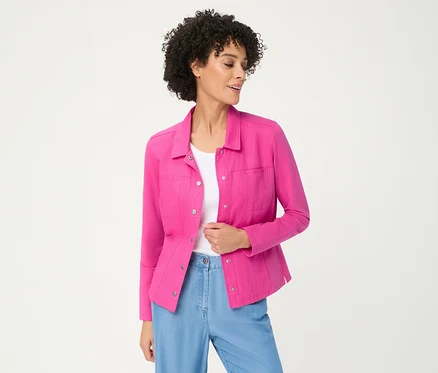 Frau mit lockigem Haar trägt eine offene pinke Olsen Jerseyjacke über einem weißen Oberteil und hellblauen Hosen, blickt zur Seite.
