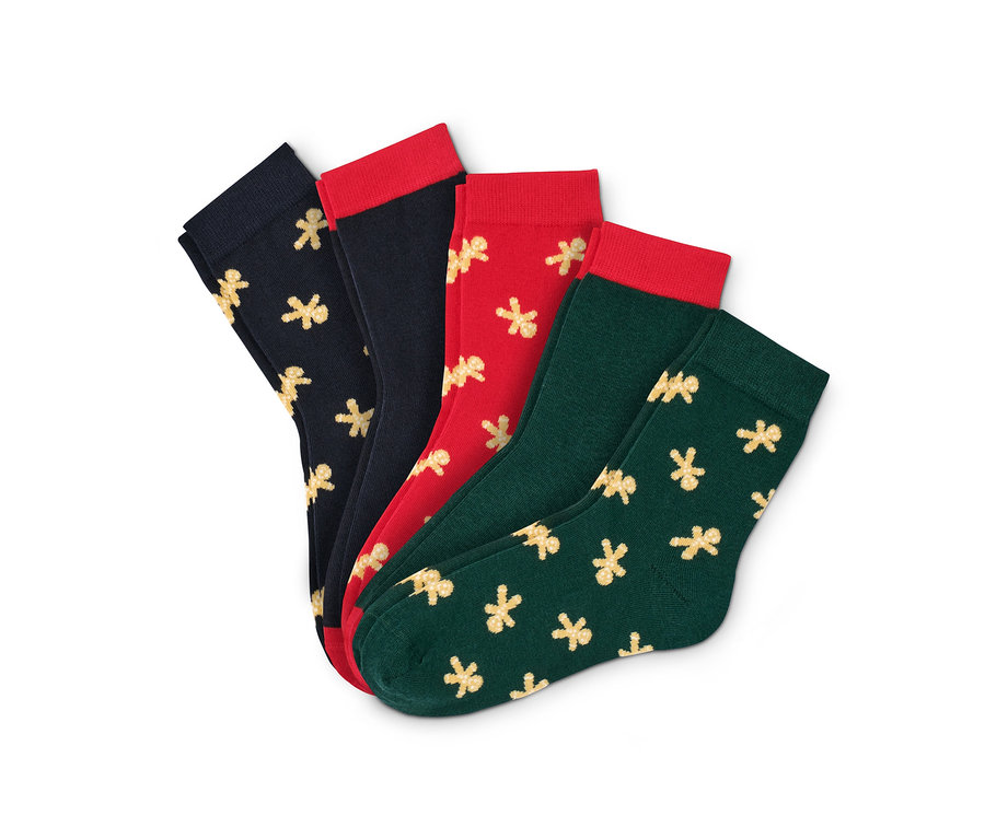 Vier Paar Socken mit Weihnachtsmotiven. Zwei schwarze, eine rote und eine grüne. Alle haben Lebkuchenmotive.
