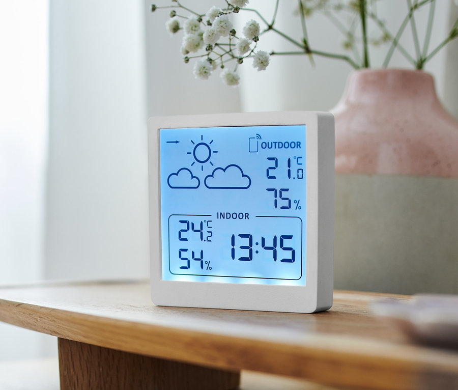 Eine weiße Wetterstation zeigt die Innen- und Außentemperatur und Luftfeuchtigkeit an.