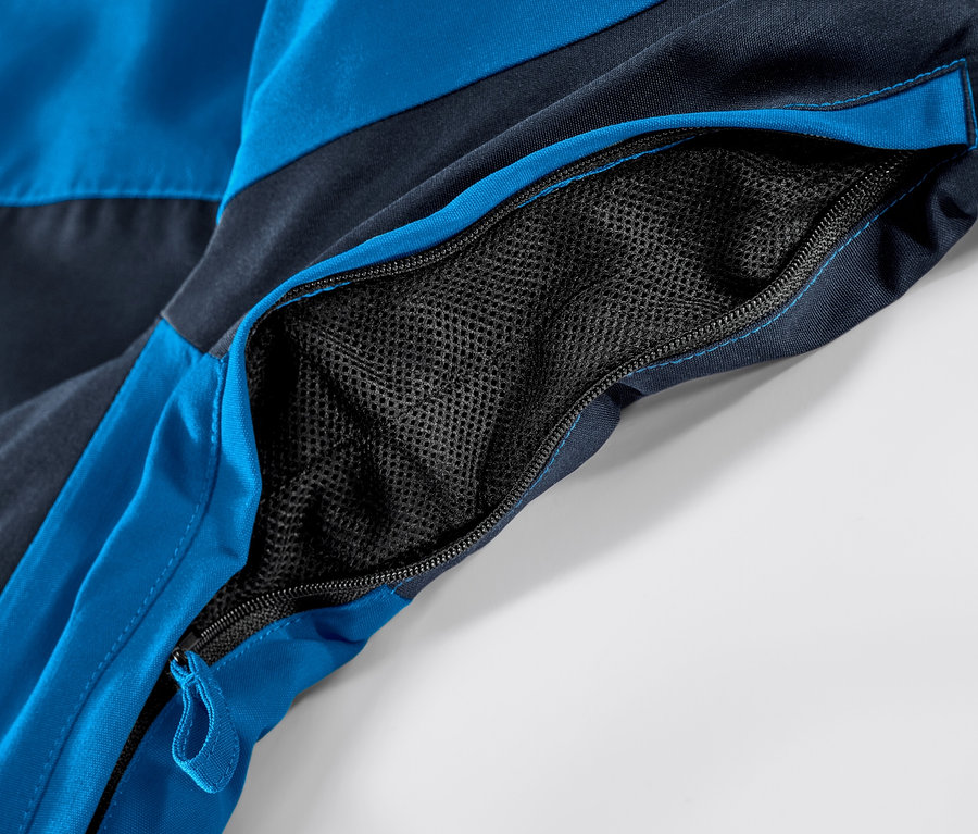 Detailaufnahme einer blauen Skijacke mit geöffneter Reißverschlusstasche.