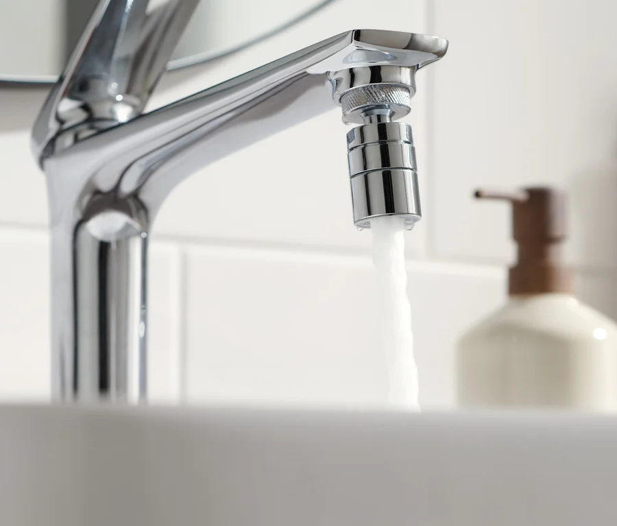 Wasser fließt aus einem Wasserhahn mit wassersparendem Wasserhahn-Aufsatz.